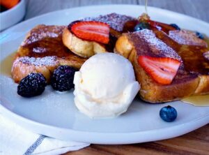 Blue Bell French Toast on a plate topped with scoop of ice cream and berries