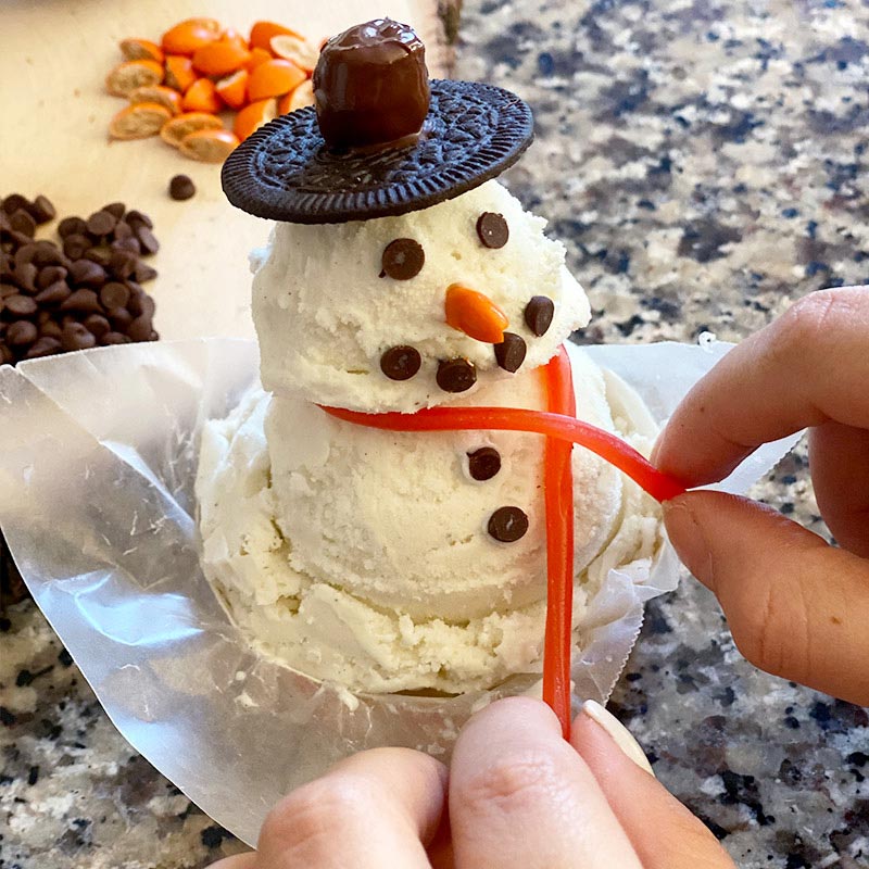 Close up of Blue Bell snowman dessert with candy scarf being put on