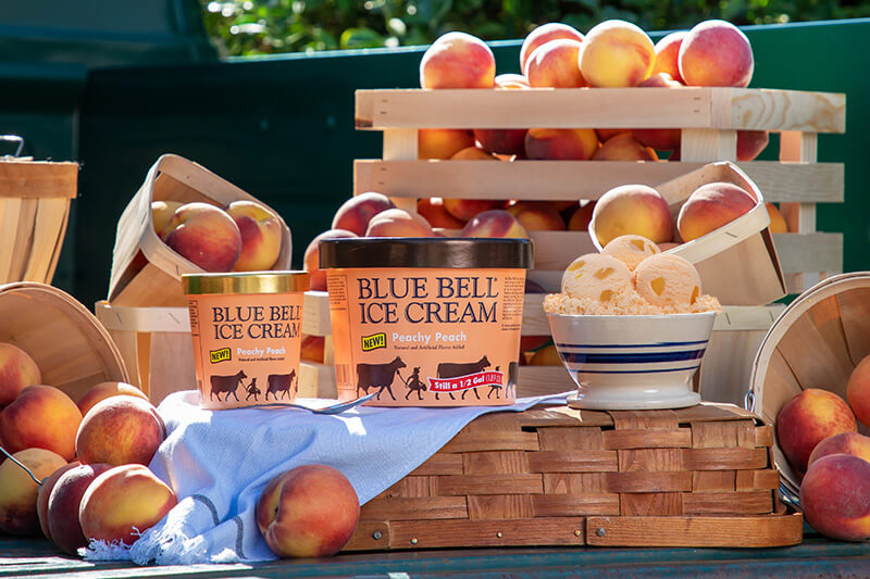 Blue Bell Peachy Peach Ice Cream half gallon and pint with crates of peaches on the bed of an vintage truck