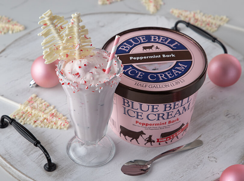 Blue Bell Peppermint Bark Milkshake with crushed peppermint candies and white chocolate tree toppers.