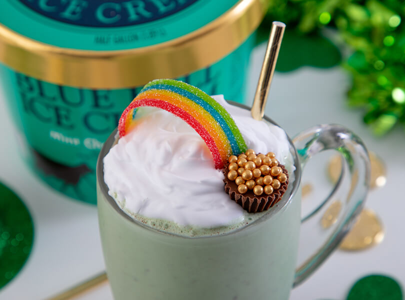 St. Patrick's Day shake made with Blue Bell Mint Chocolate Chip Ice Cream. Topped with whipped cream, rainbow strip candy, and a peanut butter cup with gold sprinkles.